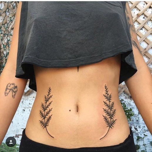 Ramos tatuados na barriga feminina