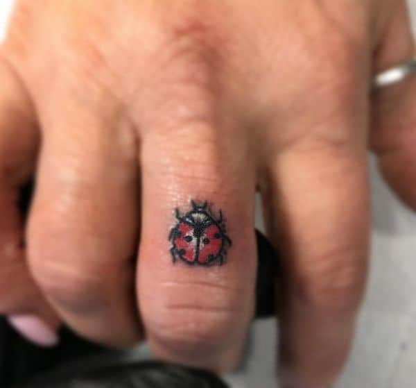 tatuagem de joaninha no dedo do meio