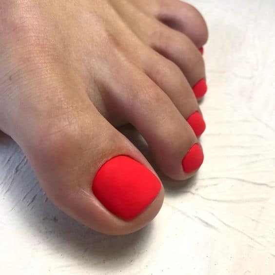 unha do pé com esmalte vermelho alaranjado fosco