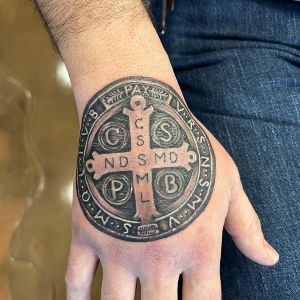 42 tatuagem medalha de São Bento na mão @jpollardtattoos
