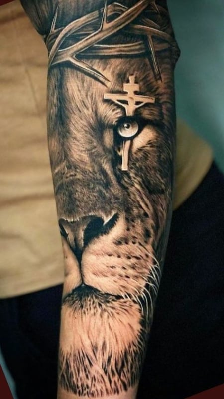 Tatuagem leão com cruz masculina no braço