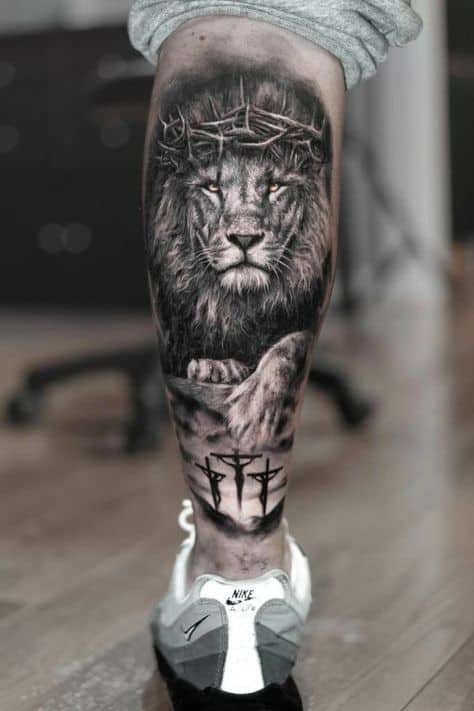 Tatuagem leão com cruz na perna