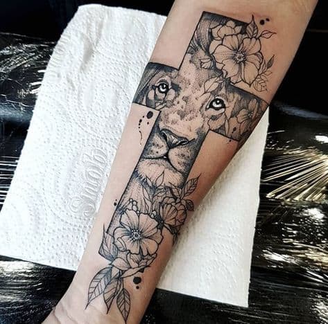 Tatuagem leão com cruz no braço com flor
